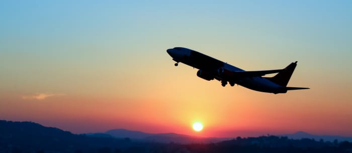 Photo of an aircraft flying with a sunset as background